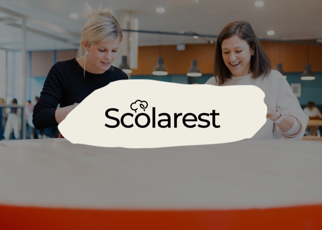 Zwei Studierende beim Mittagstisch, die essen und sich dabei unterhalten. Darüber das Logo von Scolarest.
