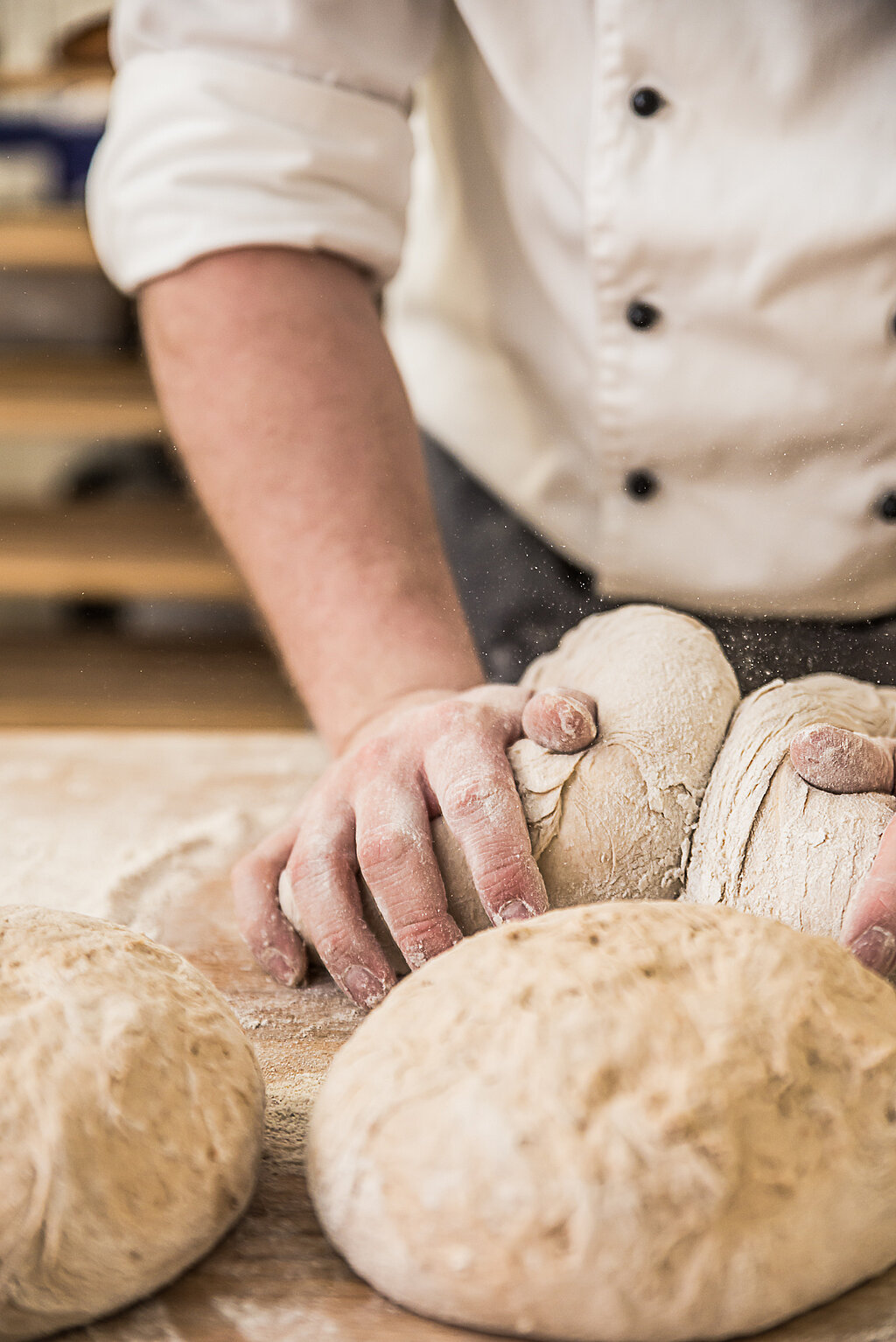Ein Bäcker in der Backstube der Brotlaibe knetet.