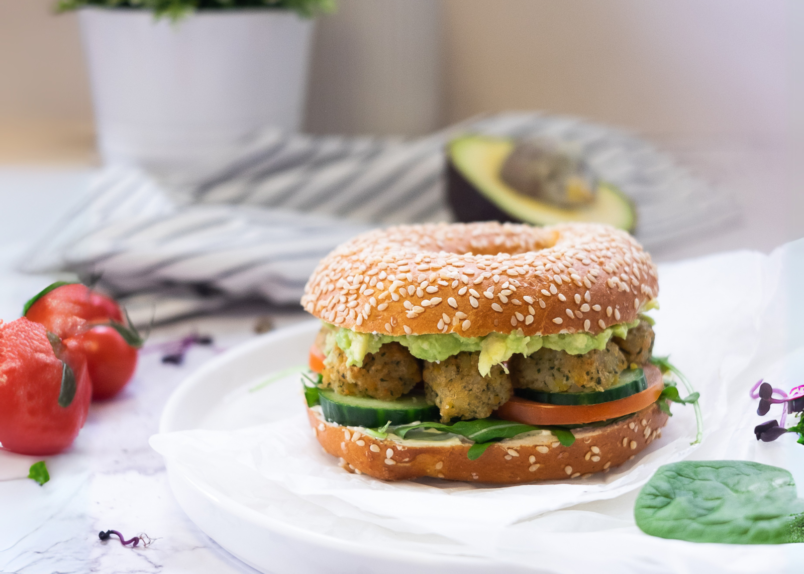 Ein Sesambagel mit Falafel, Tomaten und Rucola.
