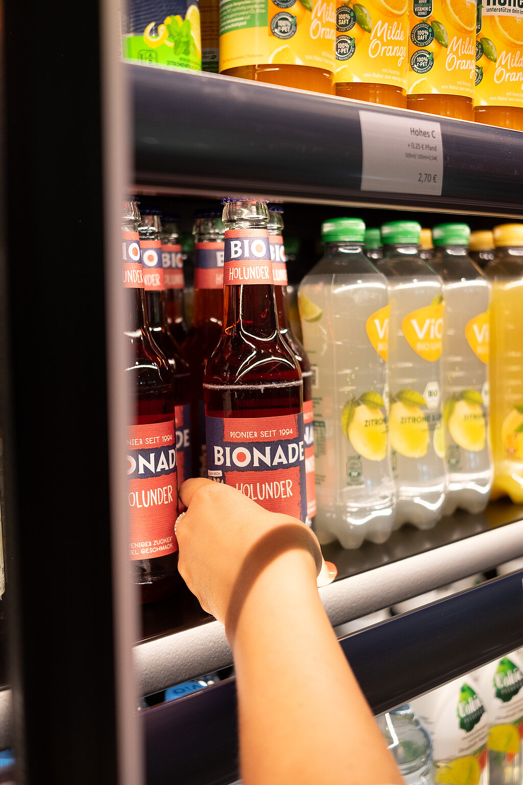 Eine Hand die in einen Kühlschrank greift und sich eine kalte Limo rausholt.