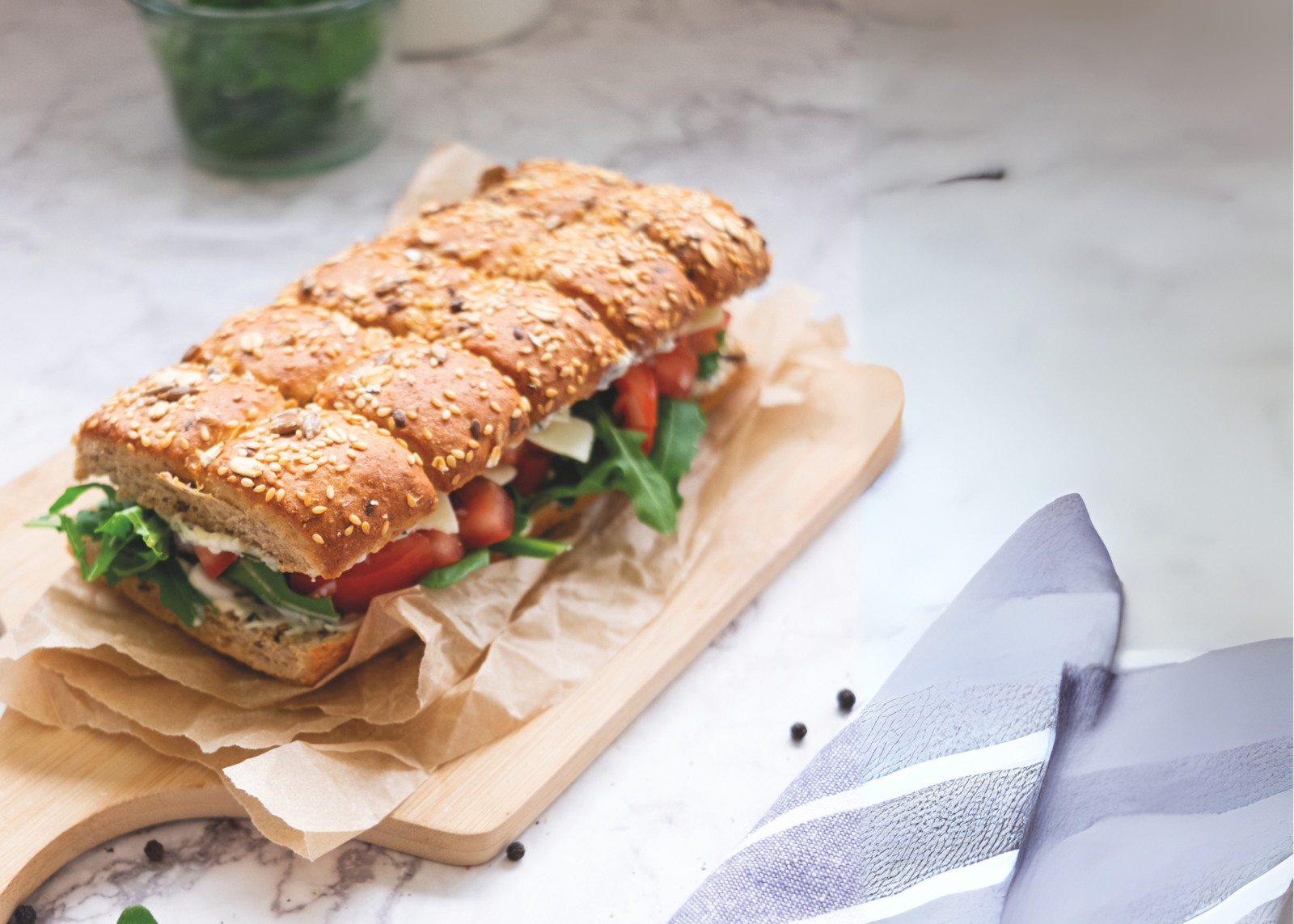 Ein Sesamsandwich gefüllt mit Tomaten und Rucola.