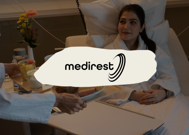 Medirest Eine junge Patientin in einem Krankenbett, die gerade ihre Mittagsmahlzeit serviert bekommt. Darüber ist das Logo der Compass Group Marke Medirest zu sehen.