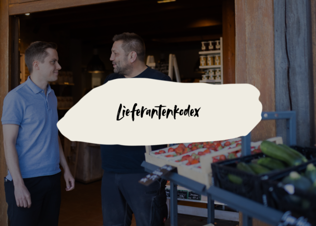 Zwei Männer, die sich vor einem Gemüseregal unterhalten. Darüber ist der Schriftzug "Lieferantenkodex" zu lesen.