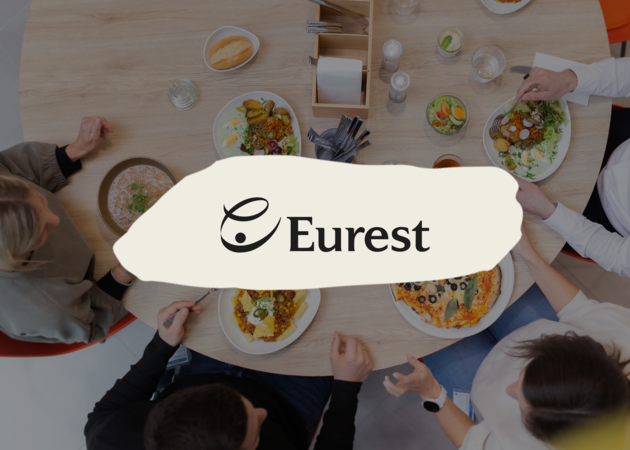 Eurest Ein reichlich gedeckter Tisch mit diversen Gerichten. Darüber das Logo der Compass Group Marke Eurest.