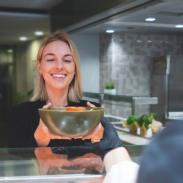 Eine junge Dame, die ihr Essen über den Counter gegeben bekommt.