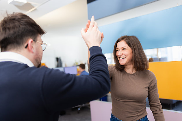 Eine junge männliche Person und eine Frau, die sich ein High-five geben.