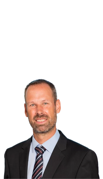 Ein Mann im Sakko und Business Kontext, der freundlich in die Kamera lächelt.