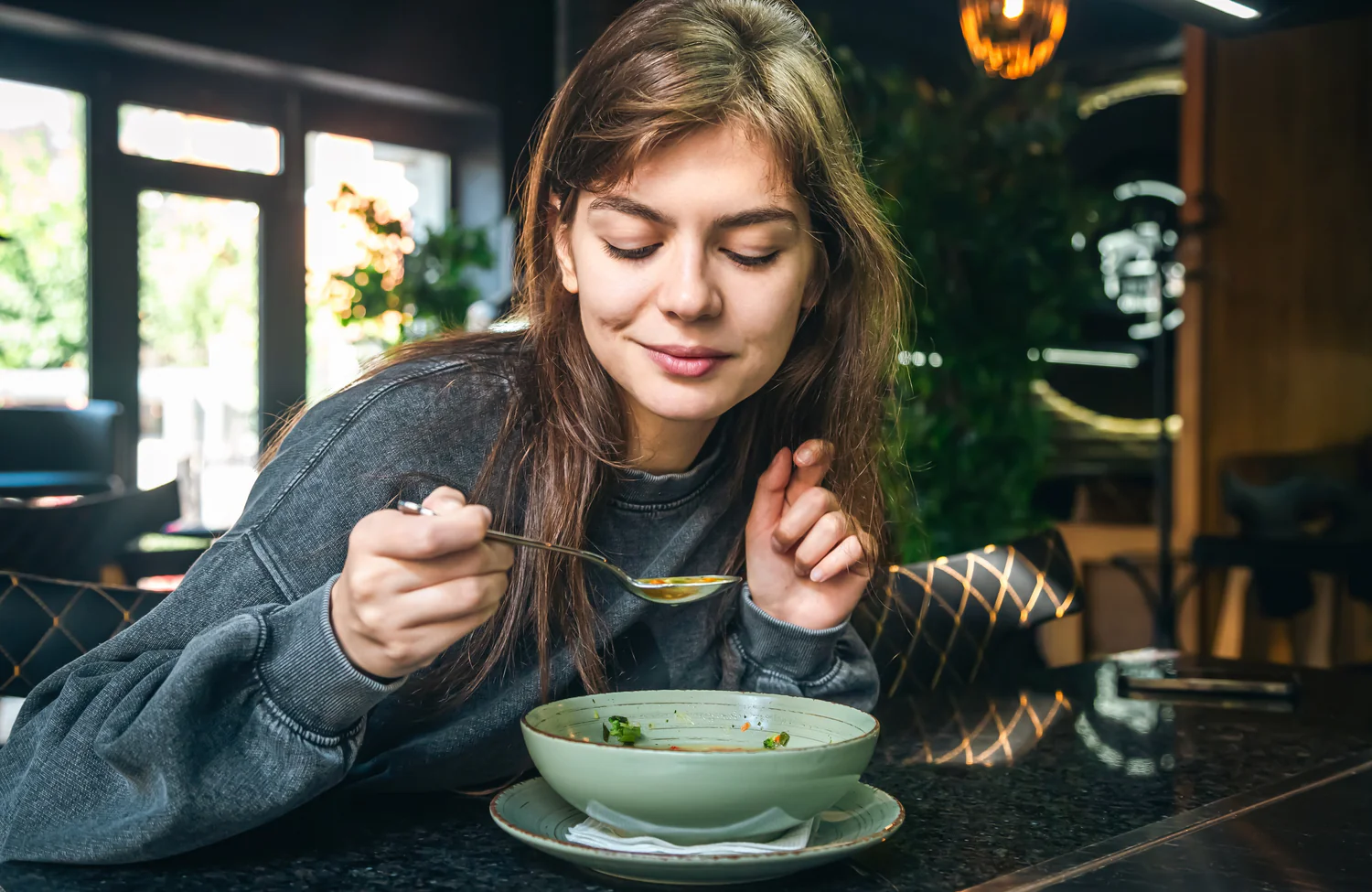 Eine junge Frau, die eine Suppe isst.