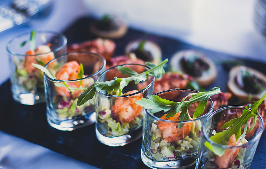 Ein fein angerichtetes Catering mit Garnelen in Gläschen und anderen Leckereien.
